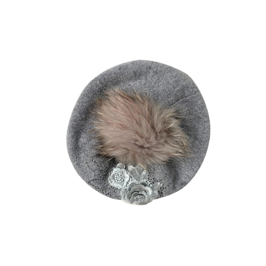 Grey beret with a fur pom-pom and decorative brooch on a white background