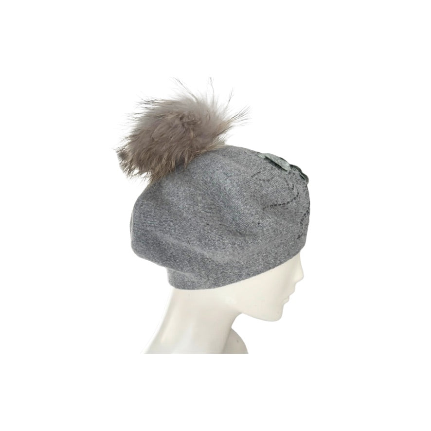 Grey beret with a fur pom-pom on a mannequin head against a white background