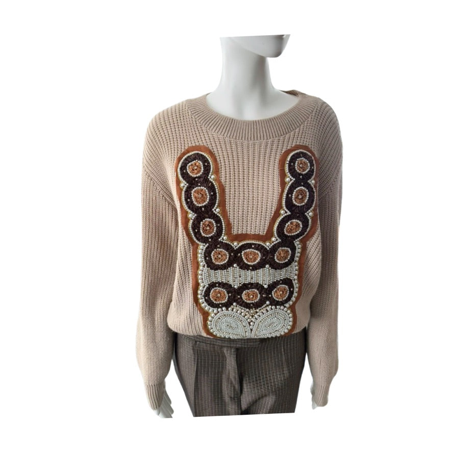 Beige sweater with decorative pattern on a mannequin against a white background
