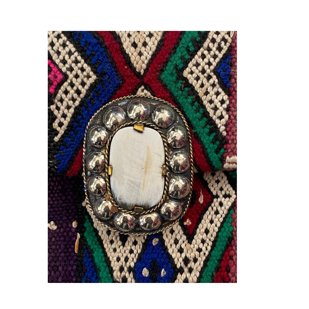 Decorative brooch with a central stone on a colorful geometric patterned background