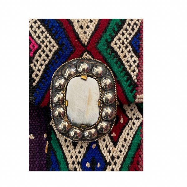 Decorative brooch with a central stone on a colorful geometric patterned background