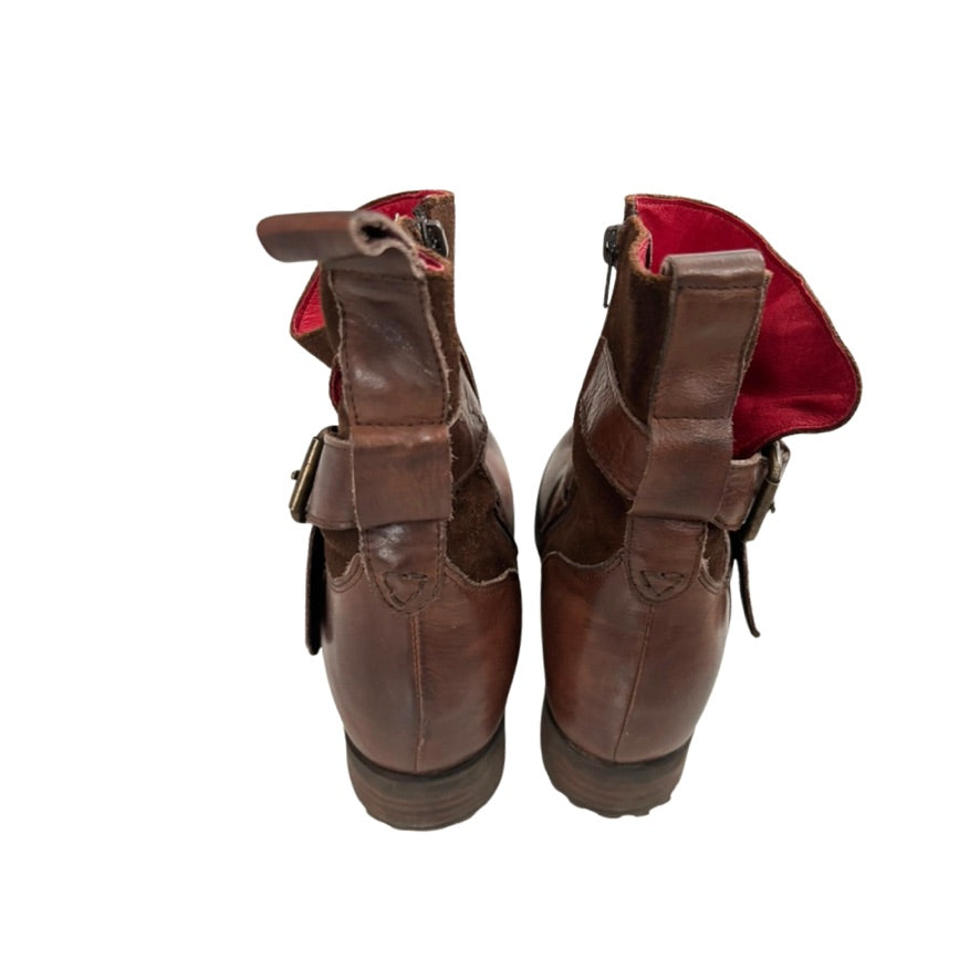 Pair of brown leather boots with red lining on a white background