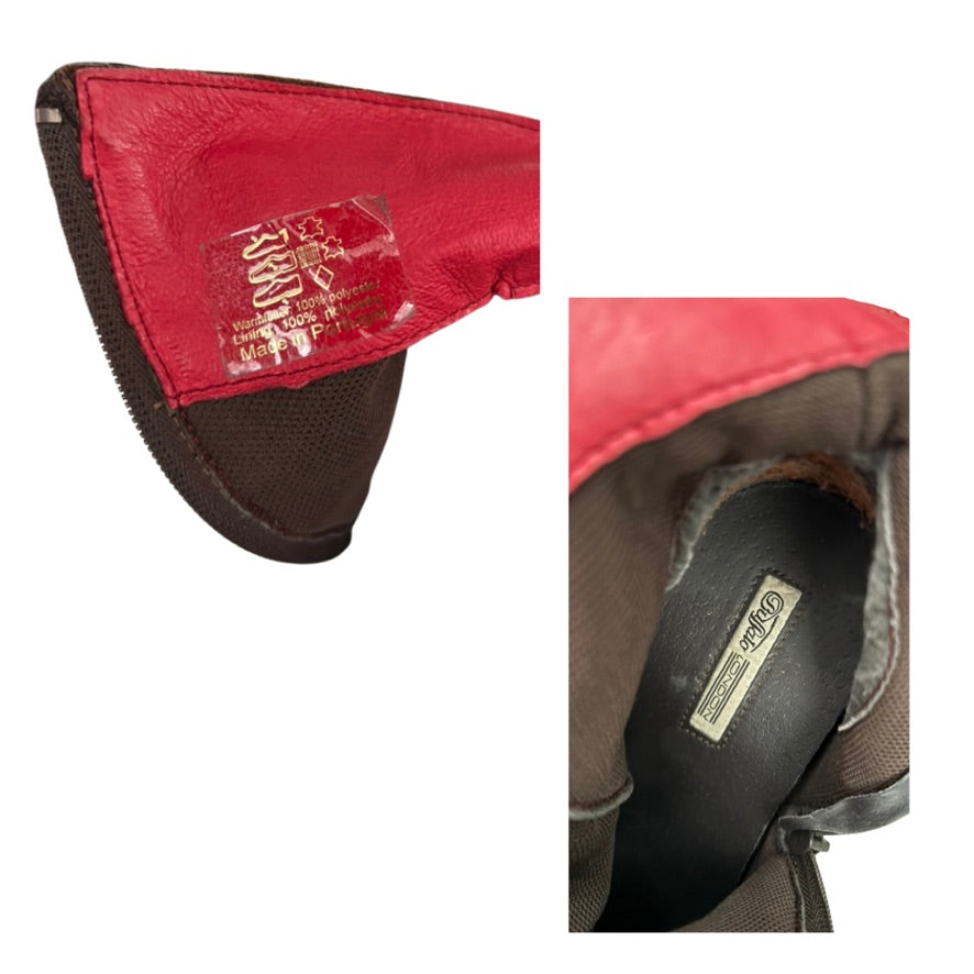 Close-up of a red and brown leather product with visible branding on a white background.