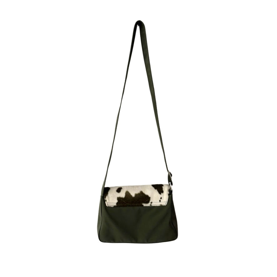 Green shoulder bag with cow print flap on a white background