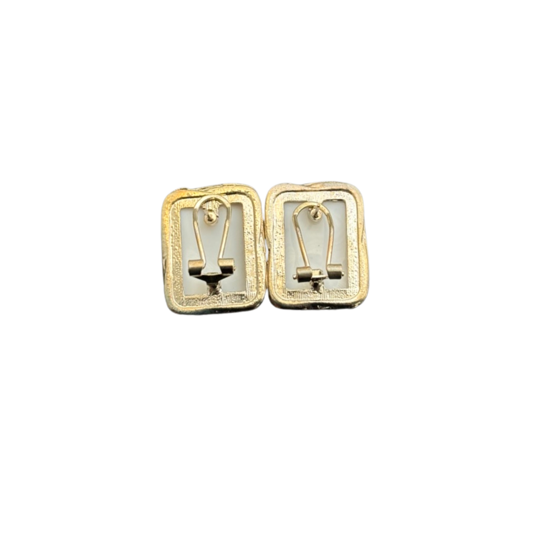Gold earrings with a design on a white background