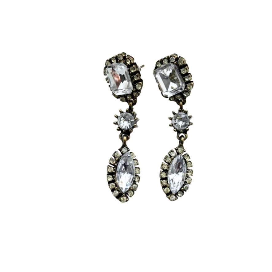 Pair of ornate earrings with clear gemstones on a white background