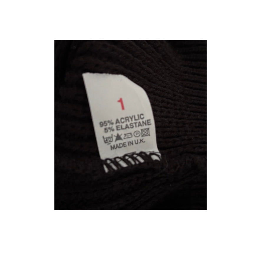 Clothing label on a black fabric background with text and symbols.