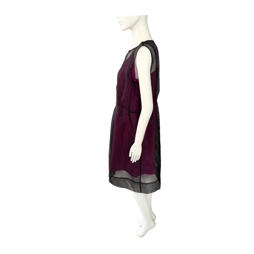 Mannequin wearing a pink dress with sheer black sleeves on a white background