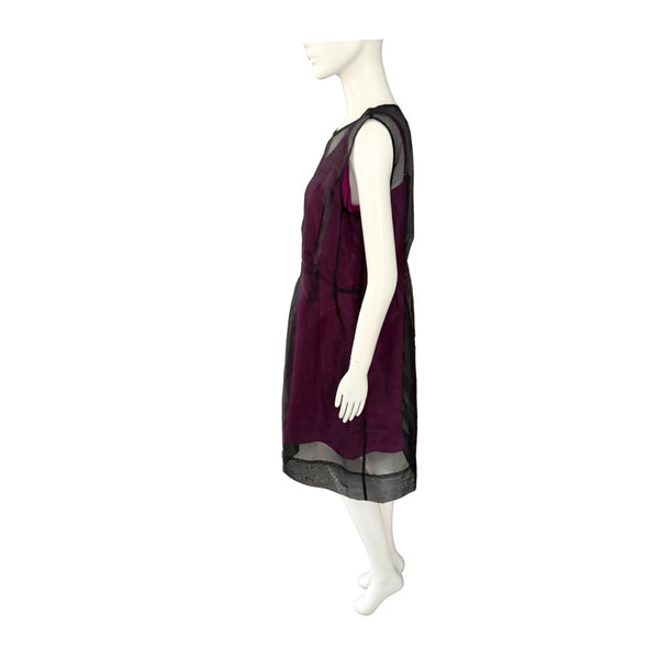 Mannequin wearing a pink dress with sheer black sleeves on a white background