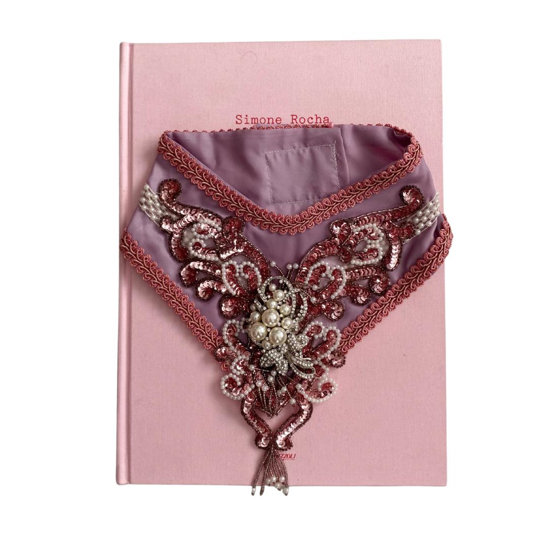 Decorative collar with intricate patterns on a pink book