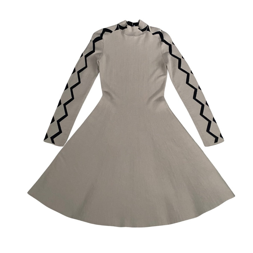 Beige dress with black zigzag patterns on long sleeves against a white background