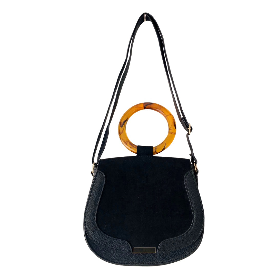 A black faux suede crossbody shoulder bag with a circular top handle and gold tone hardware, featuring a front flap closure and adjustable shoulder strap.