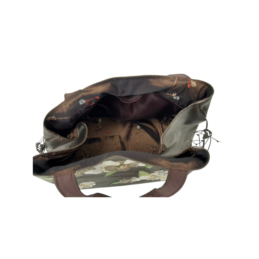 Brown leather bag with floral lining on a white background