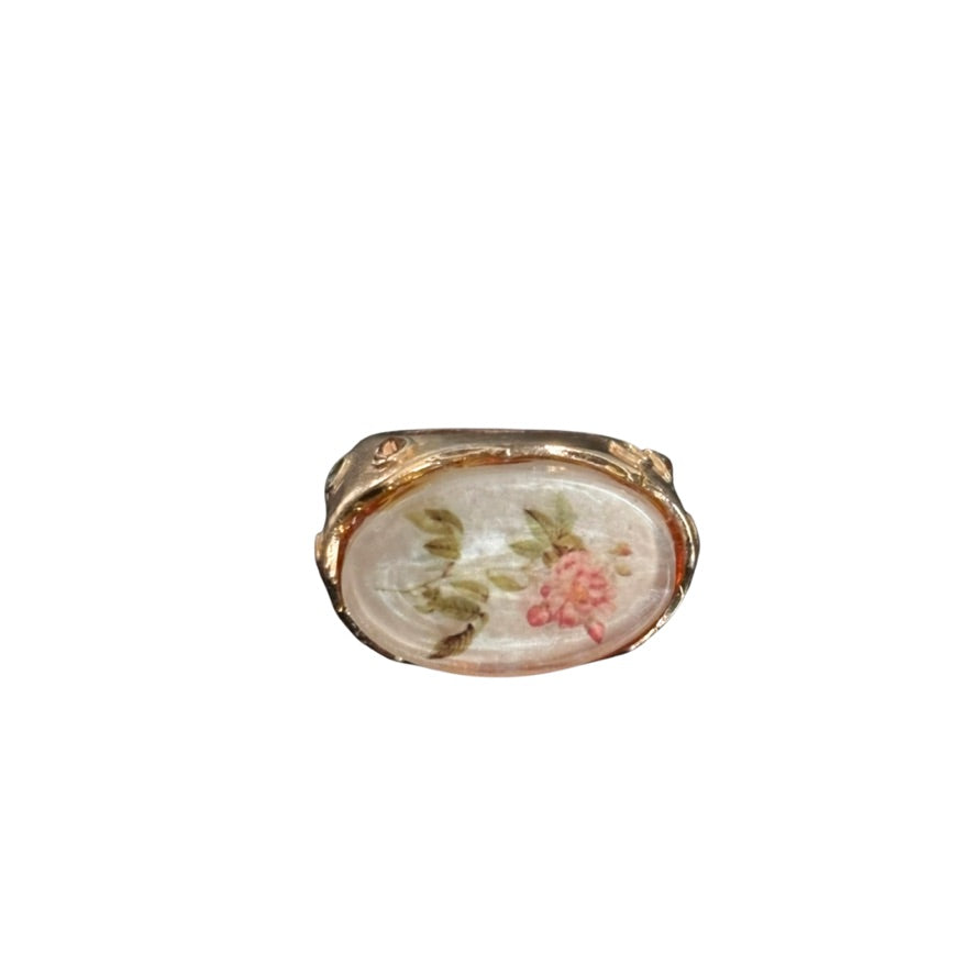 Small oval decorative item with floral design on a white background