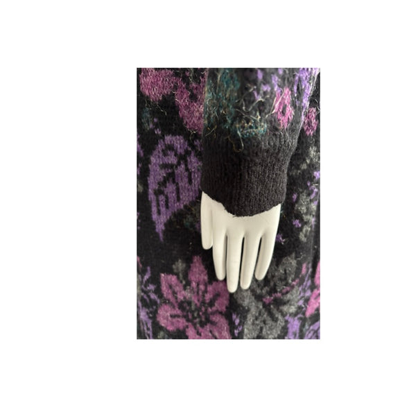 Black knit sleeve on a mannequin hand against a patterned background