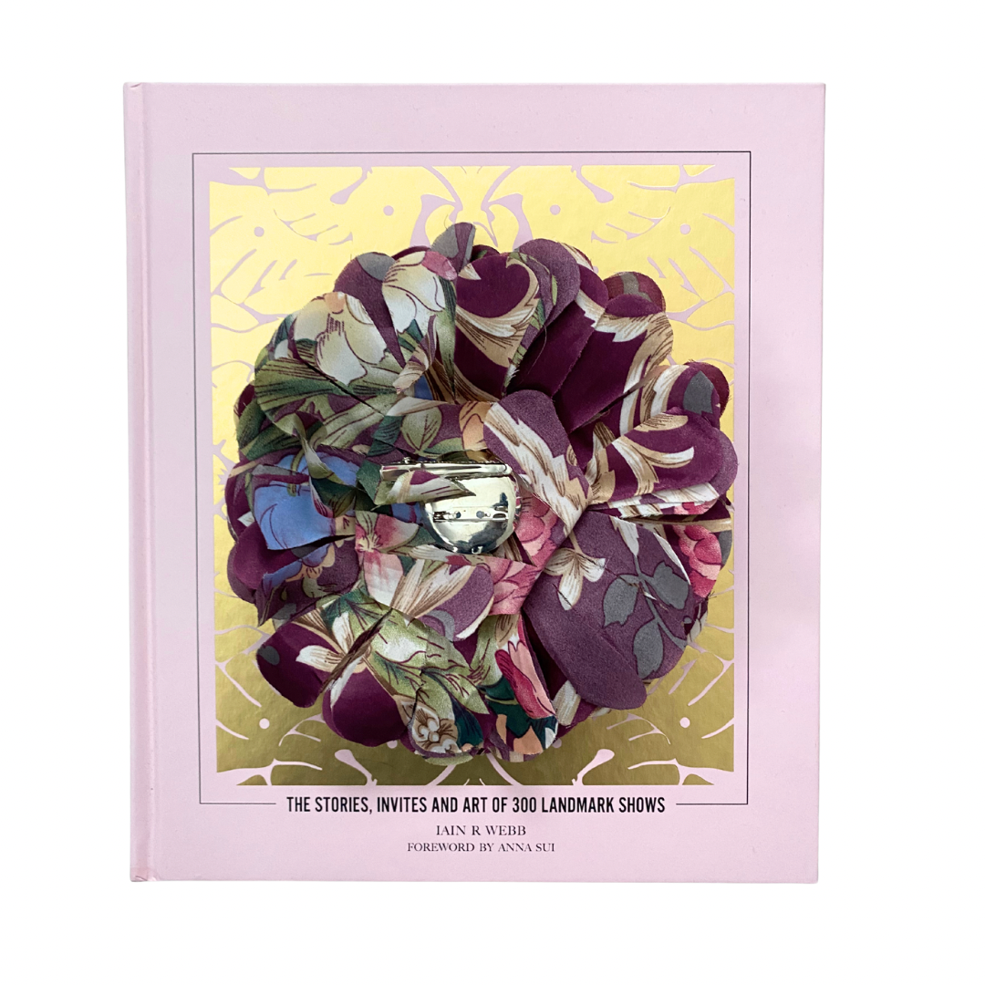 Fabric flower brooch in plum and multicolour patterned fabric with layered petal design, placed on light wooden floor.