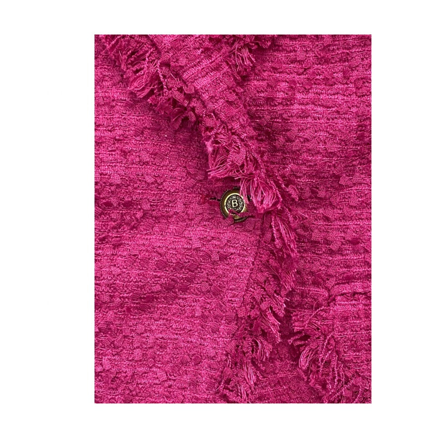 Close-up of a pink textured fabric with ruffled edge and a button on a white background