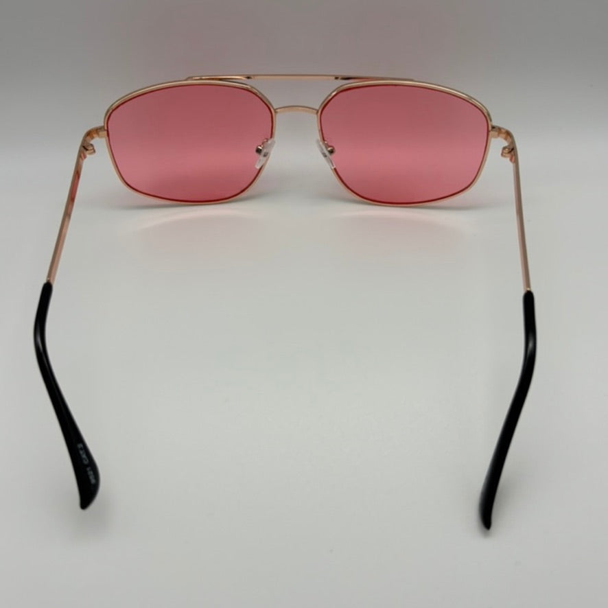 Sunglasses with pink lenses and gold frames on a light gray background