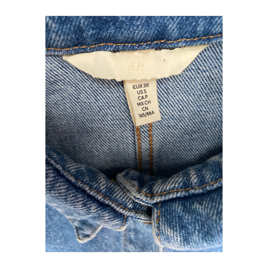 Close-up of a denim garment with a size label on a white background
