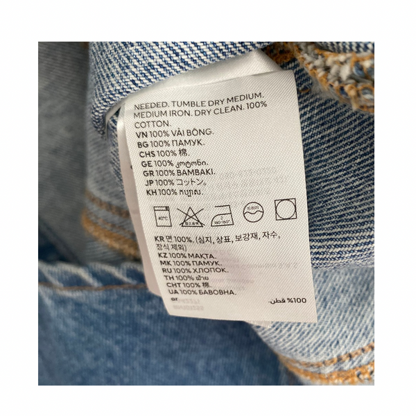 Clothing label on a denim fabric with text and symbols.