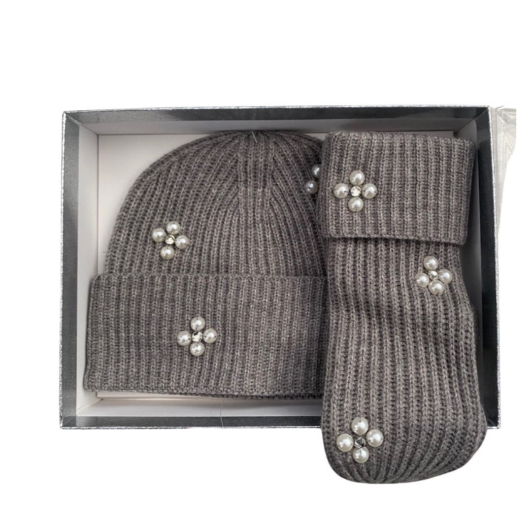 Grey knit hat and mittens set with decorative elements in a box on a white background