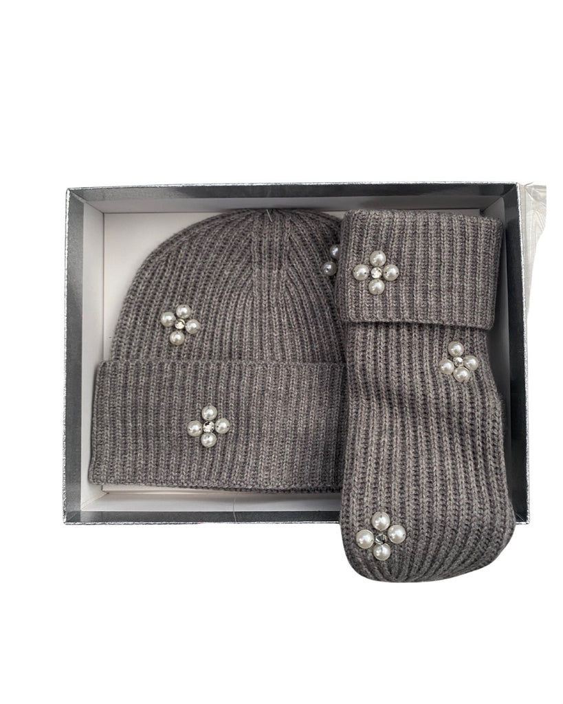 Grey knit hat and mittens set with decorative elements in a box on a white background