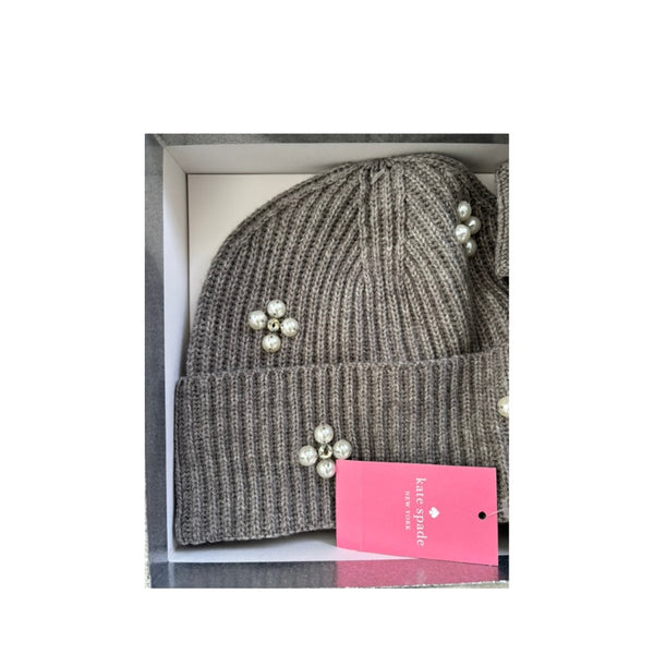 Grey knit beanie with pearl embellishments in a box with a pink Kate Spade tag.