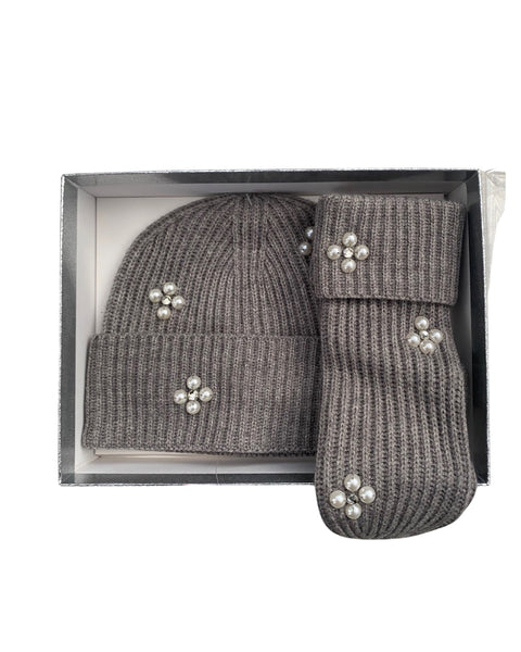 Grey knit hat and mittens set with decorative elements in a box on a white background