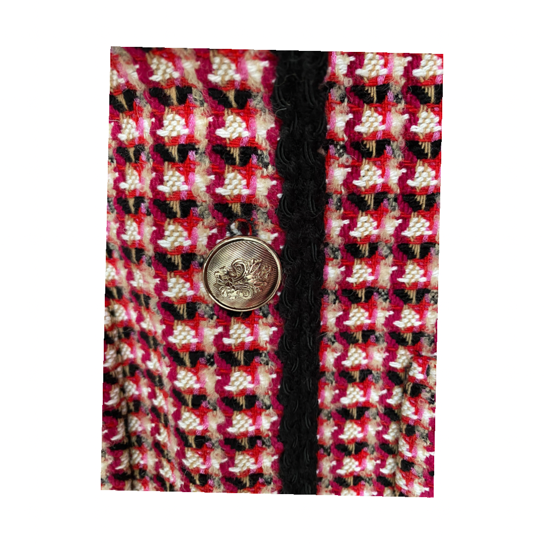 Close-up of a patterned fabric with a button and black piping on a white background