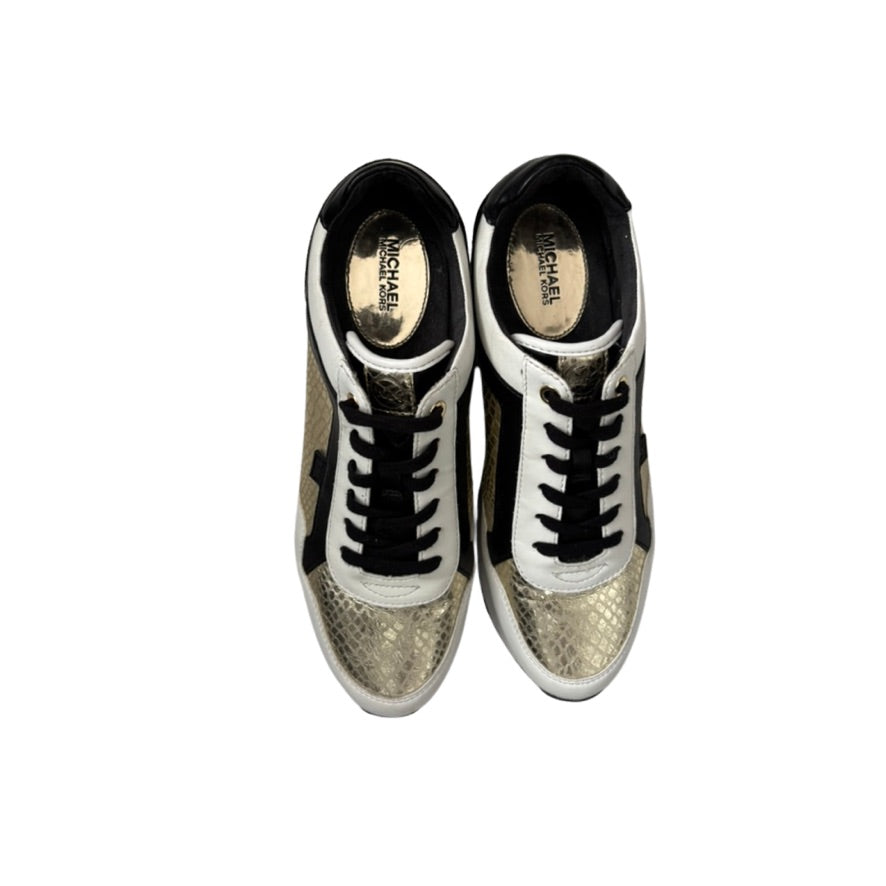 Pair of shiny gold sneakers with black laces on a white background