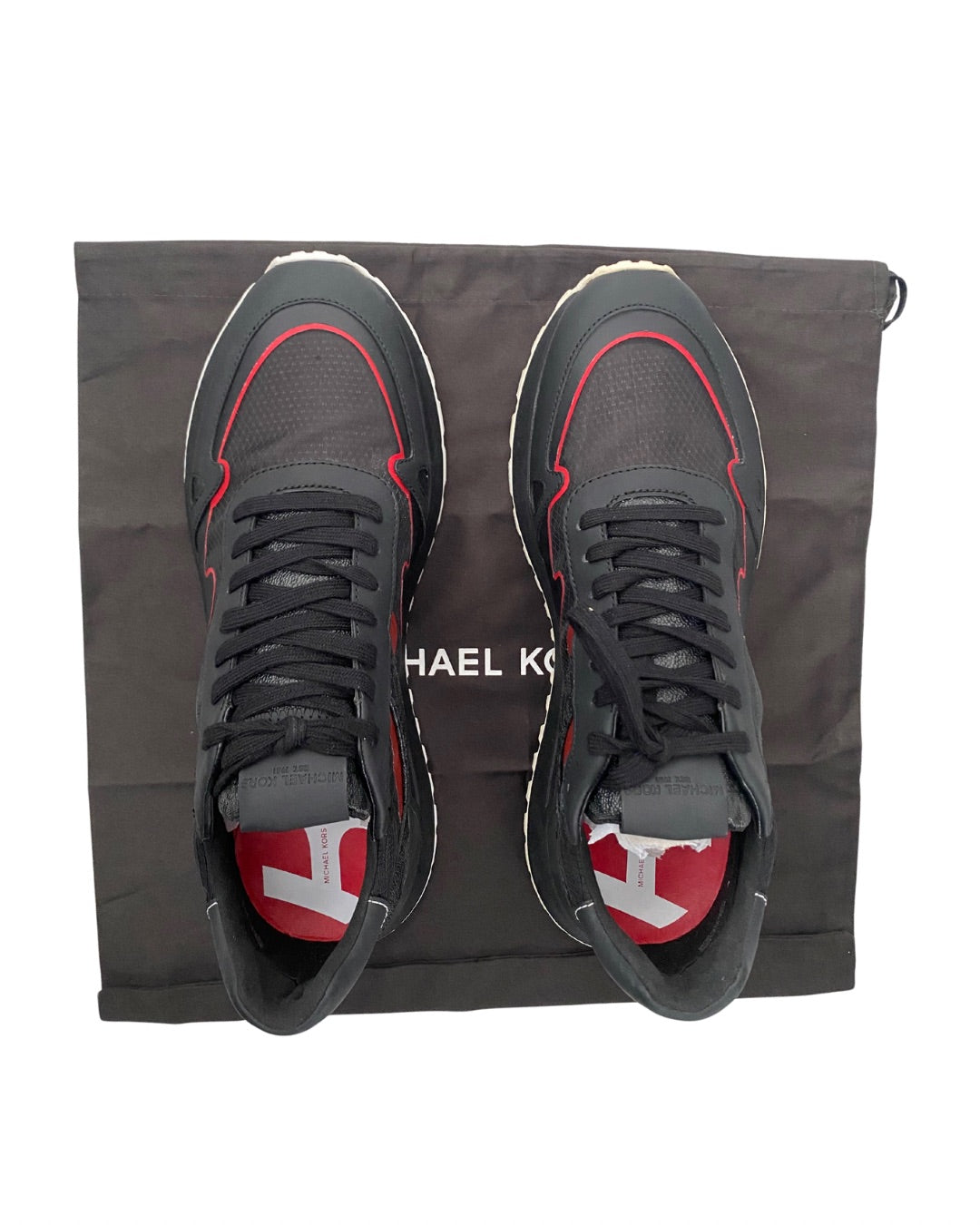 Black sneakers with red accents on a Michael Kors bag