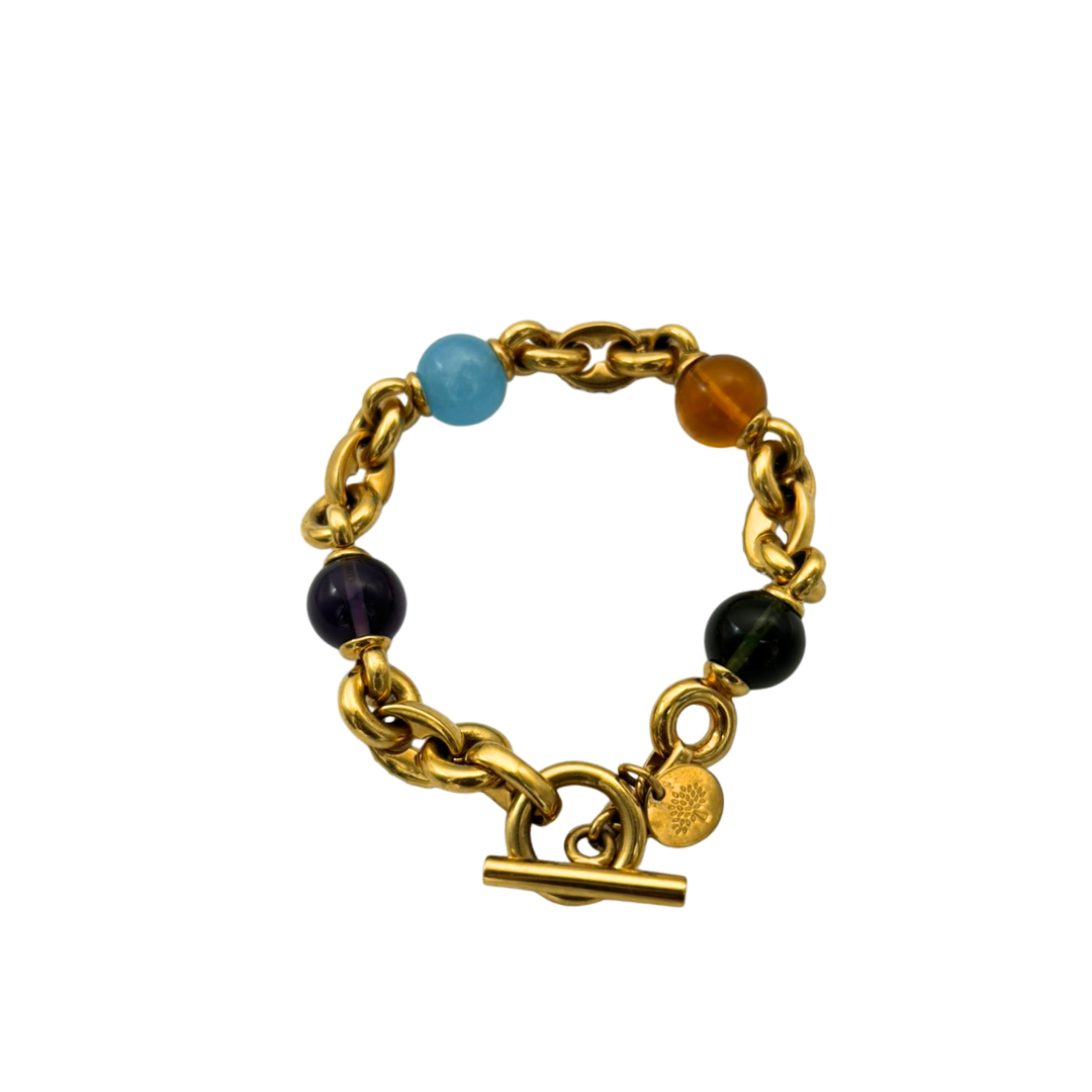 Gold chain bracelet with colored beads on a white background