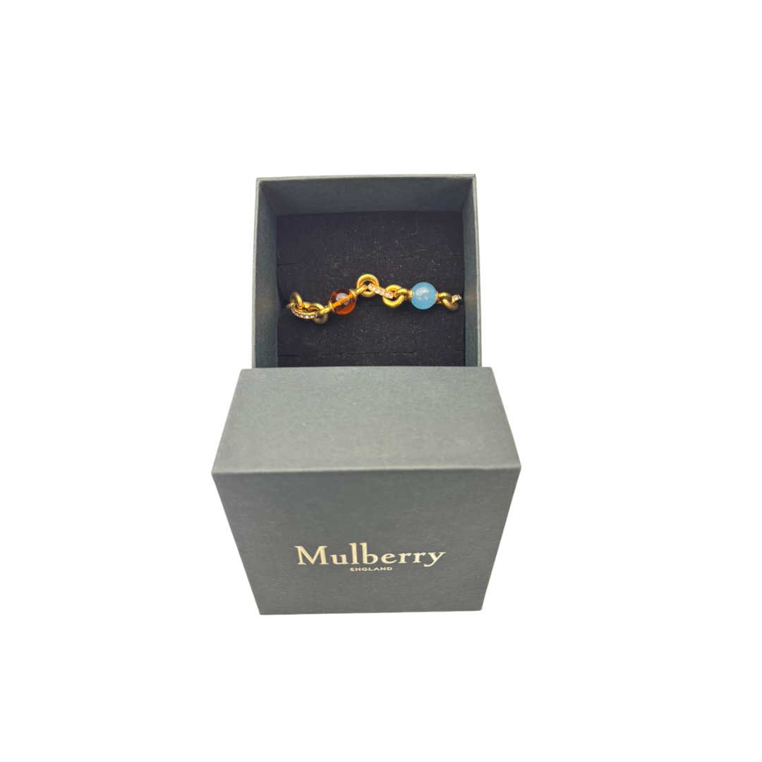Gold bracelet with blue gemstone in a Mulberry box on a white background