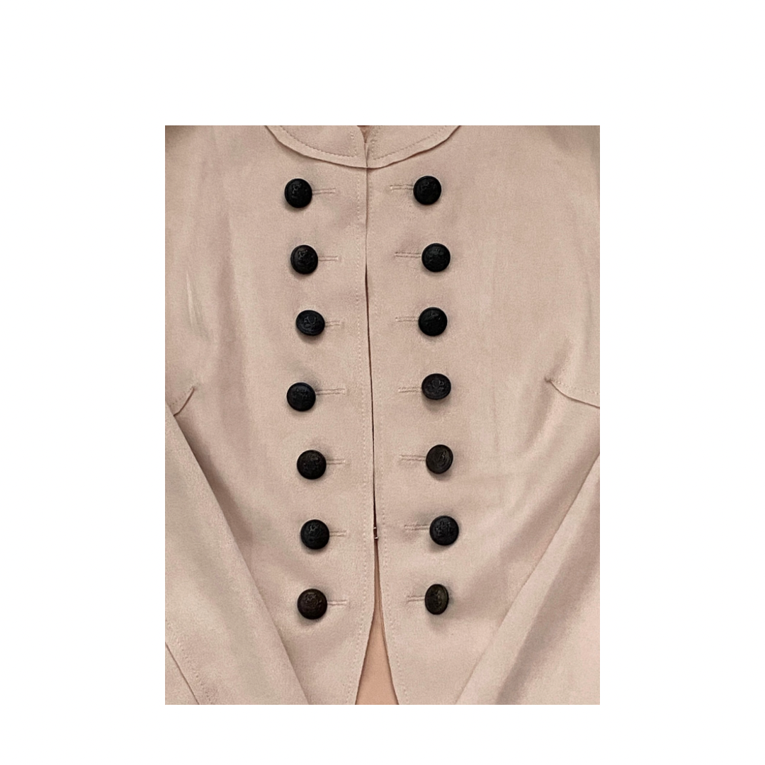 Close-up of a pale pink jacket with black buttons on a white background