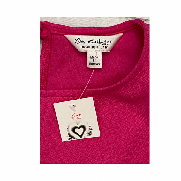 Close-up of a pink garment with a label and tag on a white background