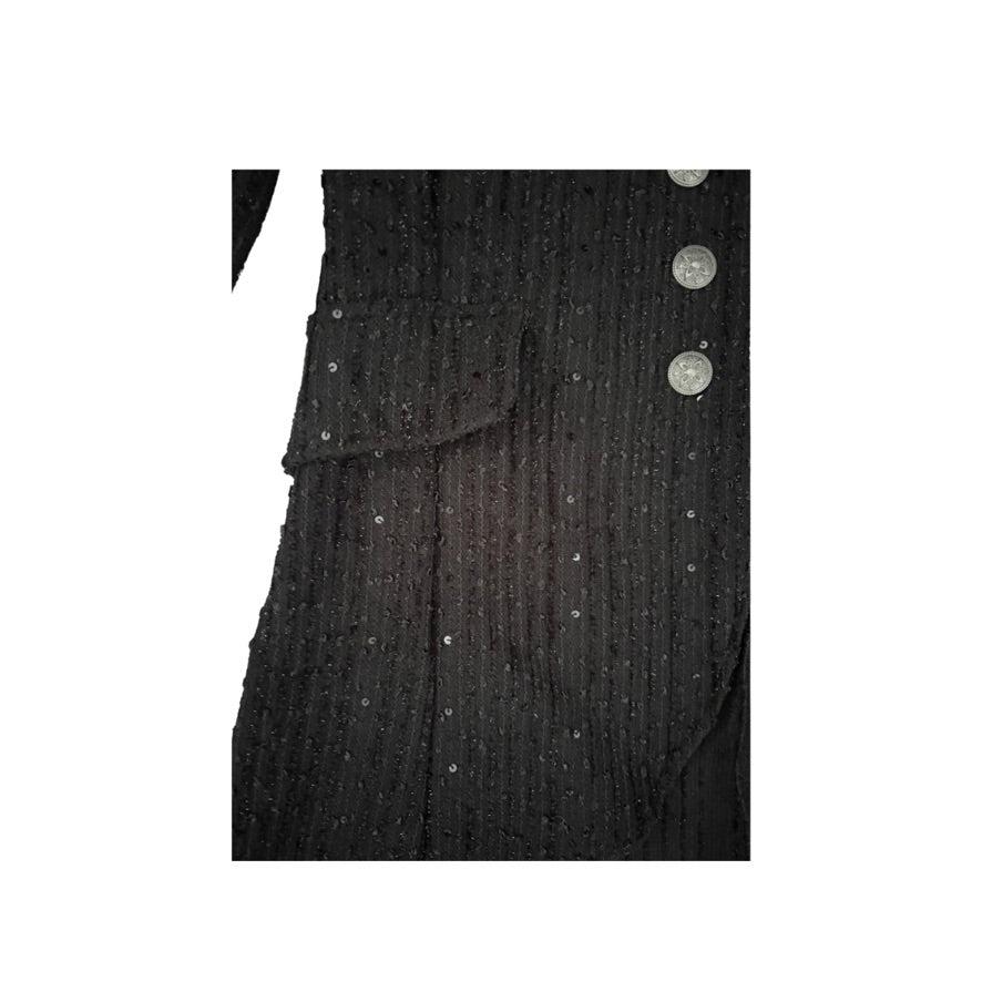 Close-up of a black textured garment with buttons on a white background