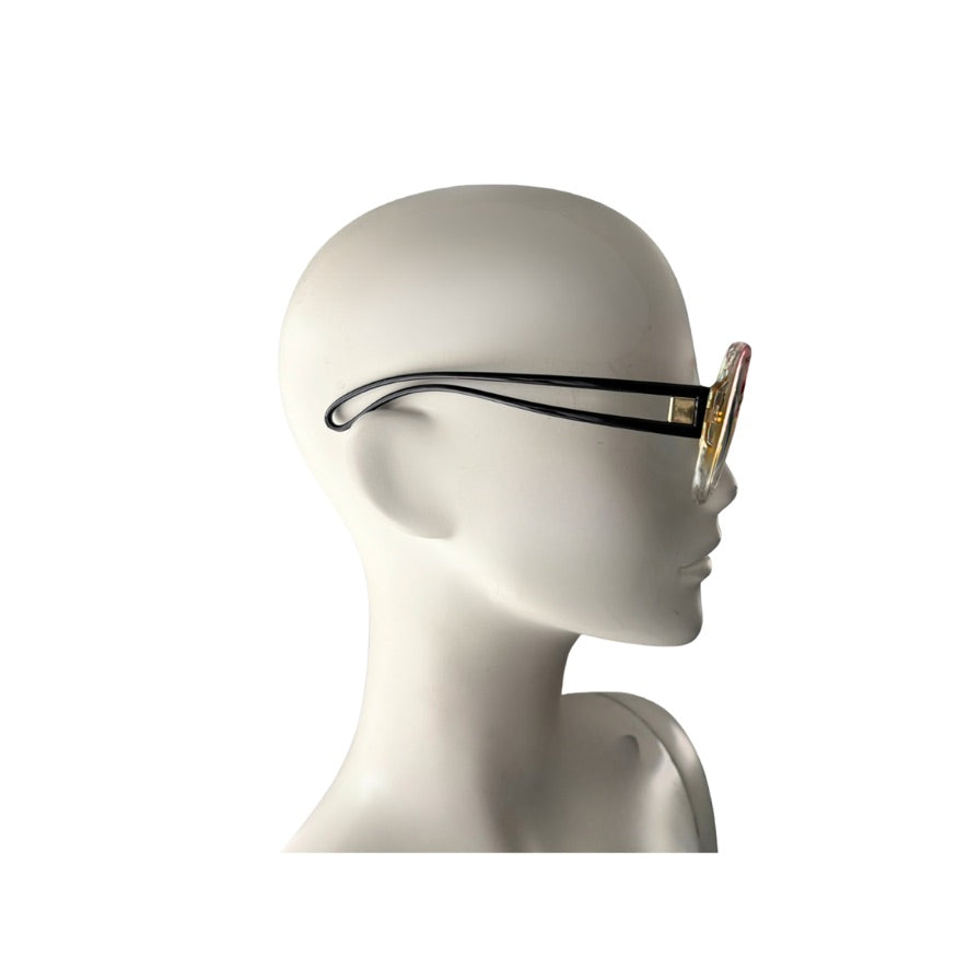 Mannequin head wearing a pair of sunglasses with a black frame and gold accents on a white background.