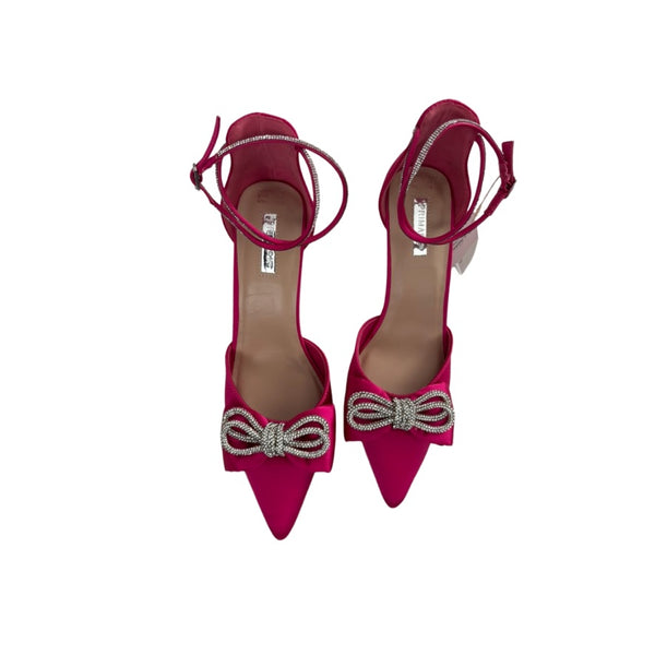 Pair of pink high-heeled shoes with decorative bows on a white background