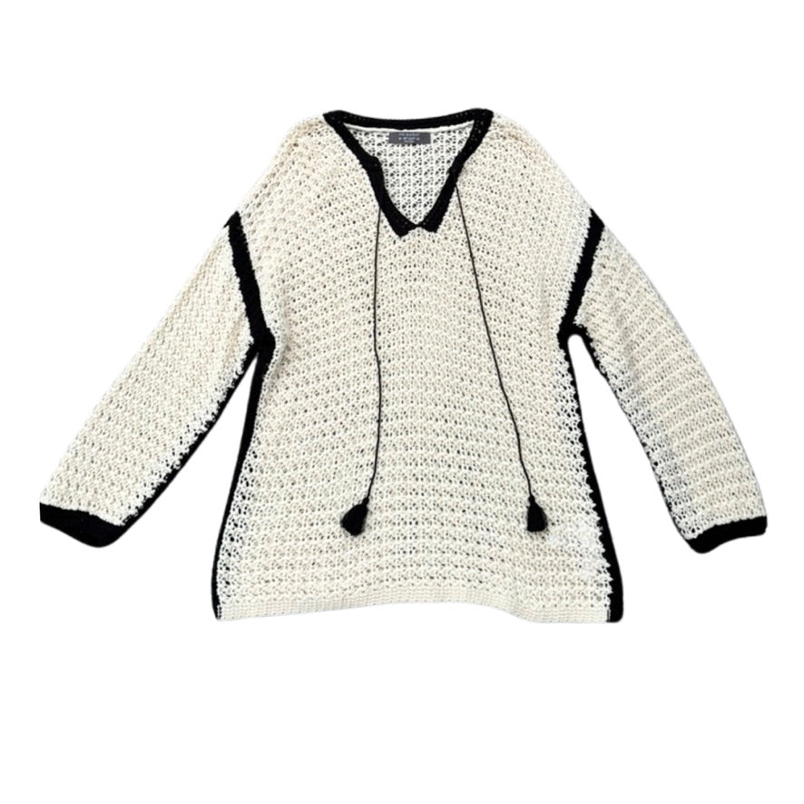 White crocheted sweater with black trim on a white background