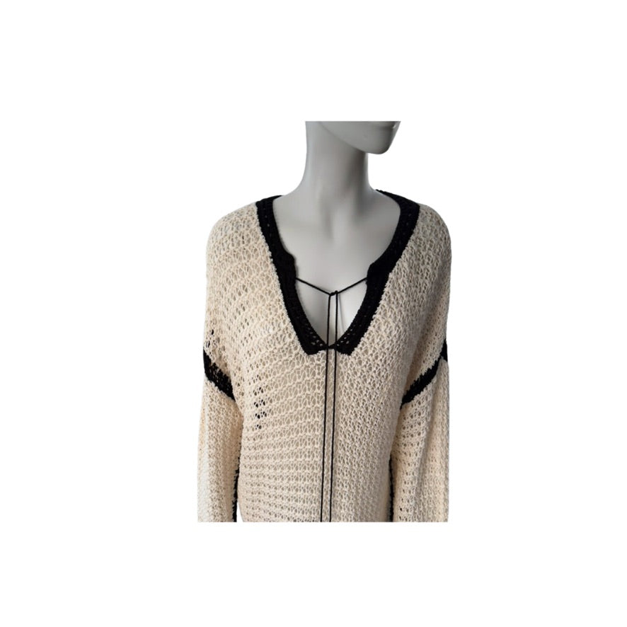 Mannequin wearing a beige cardigan with black trim on a white background