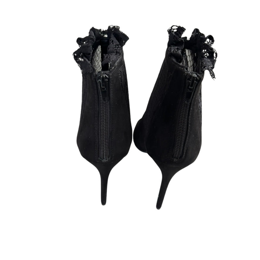 Pair of black high-heeled shoes with decorative elements on a white background