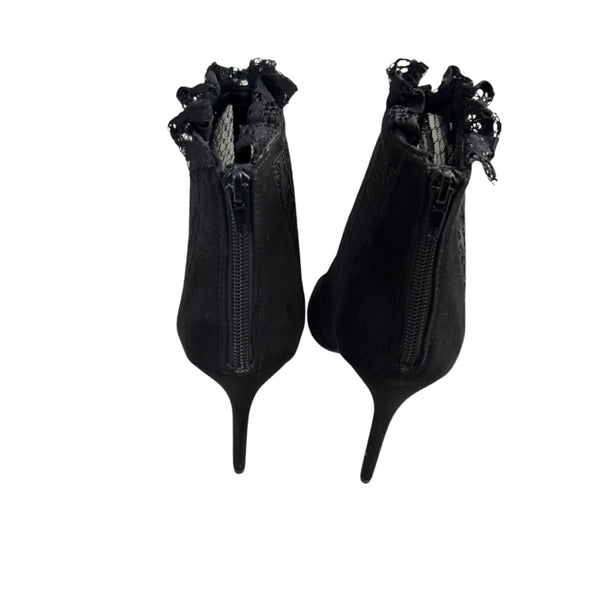 Pair of black high-heeled shoes with decorative elements on a white background