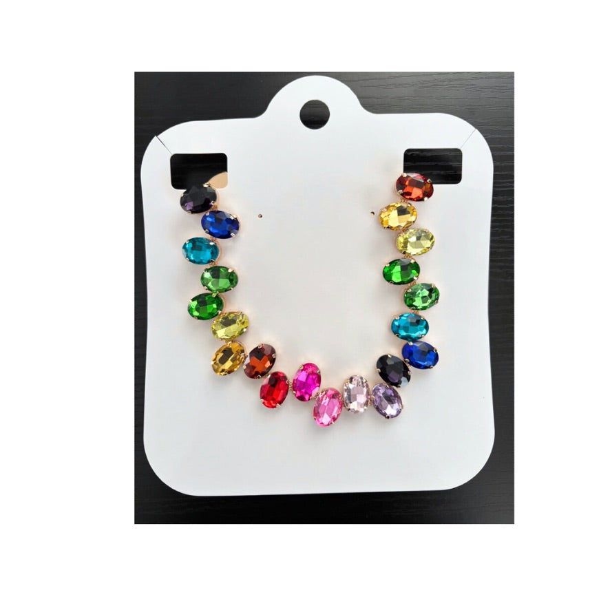 Colorful gemstone earrings on a white card with a black background