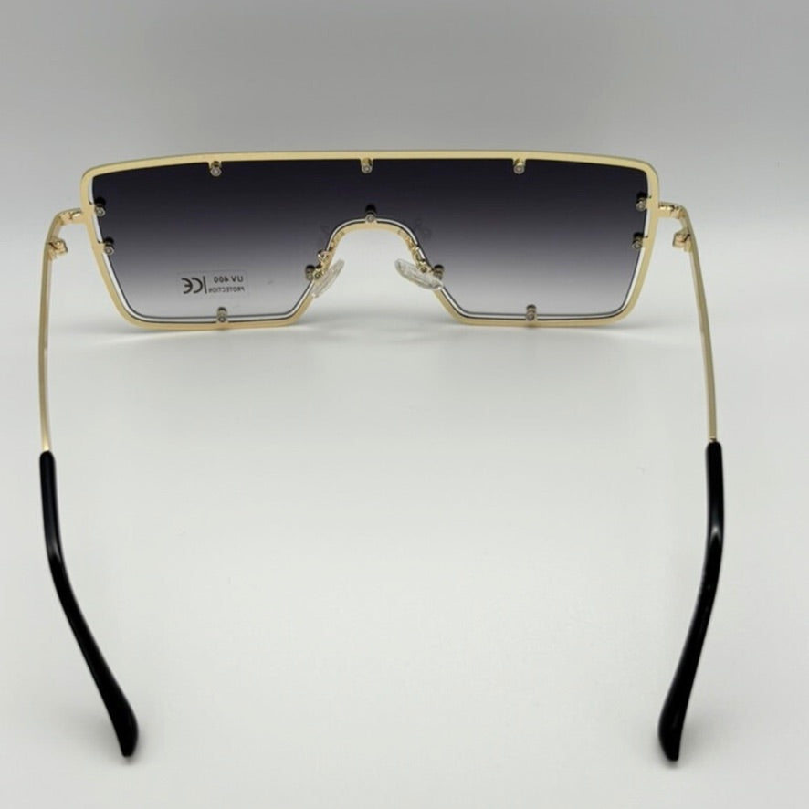Gold-framed sunglasses with black gradient lenses on a gray background