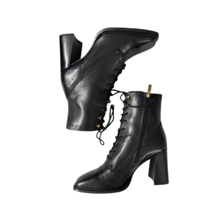 Pair of black leather boots with high heels on a white background