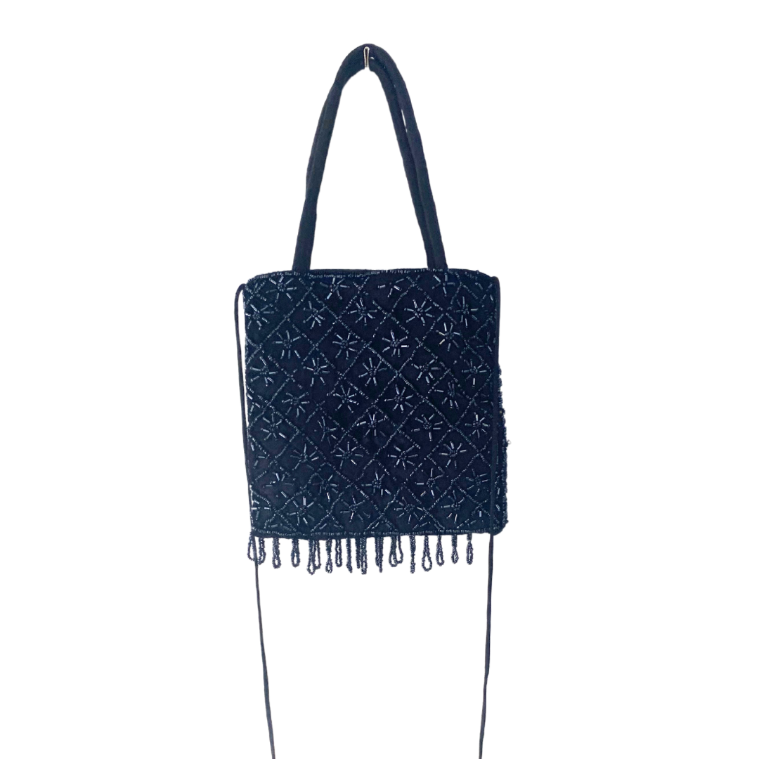 A black navy beaded handbag with a floral pattern and fringe detail, featuring a zip top closure and long shoulder strap.