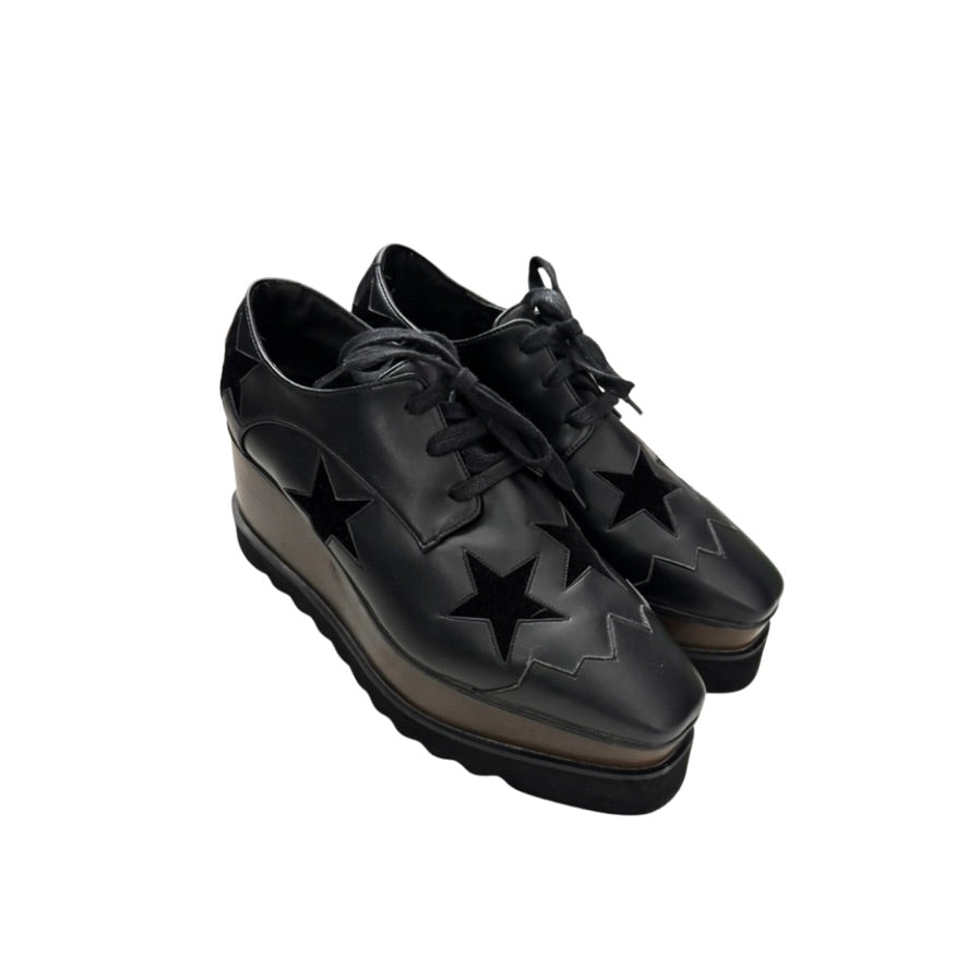 Black brogues with star designs on a white background
