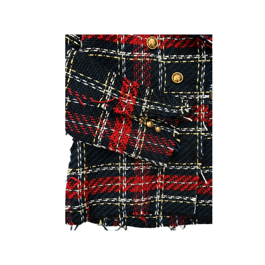 Close-up of a plaid fabric with red, black, and gold colors on a white background.