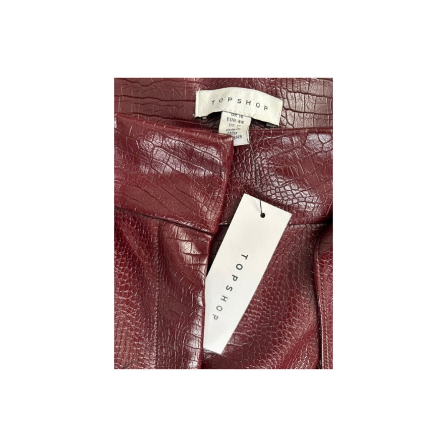 Close-up of burgundy leather shorts with Topshop tags on a white background