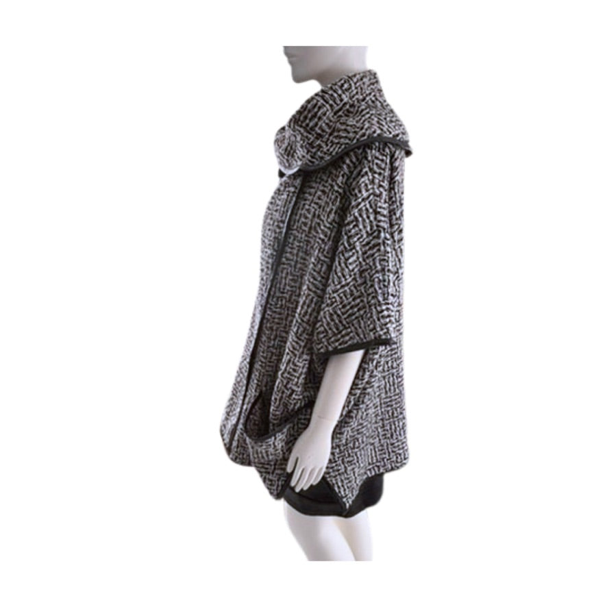 Mannequin wearing a black and white patterned poncho on a white background